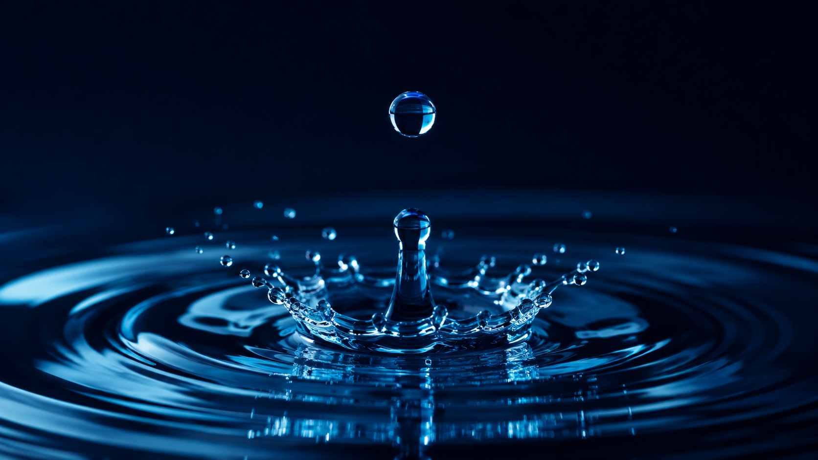 Macro fotografía de una gota de agua pura y cristalina cayendo sobre superficie calma